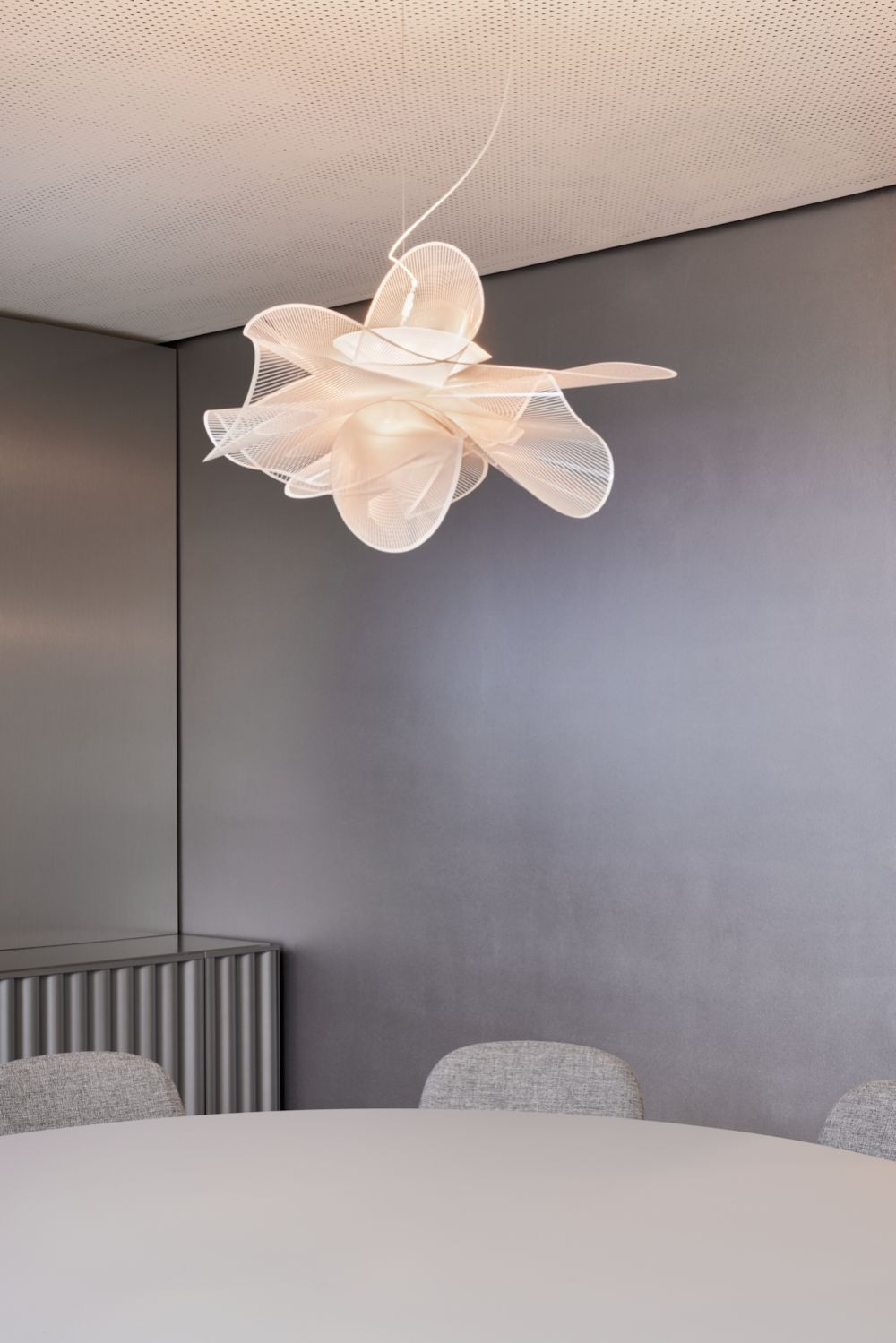 Moderner Konferenzraum mit skulpturaler Hängelampe; elegantes, minimalistisches Design. Symbol für energieeffiziente Beleuchtung im Unternehmen.