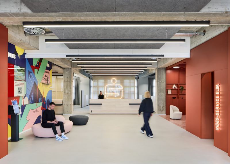 Ein Empfangstresen aus Holz und warme Rottöne heißen die Besucher der Stadtsparkasse Düsseldorf Willkommen | Bank Architekt bkp